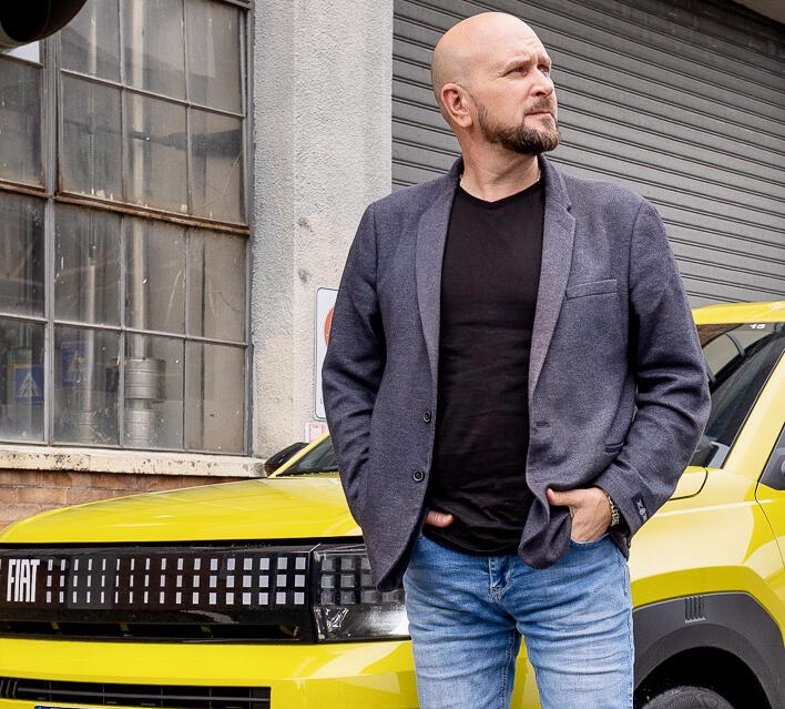 Tim Barnes-Clay Shot of Tim Barnes-Clay stood in front of a yellow Fiat car.